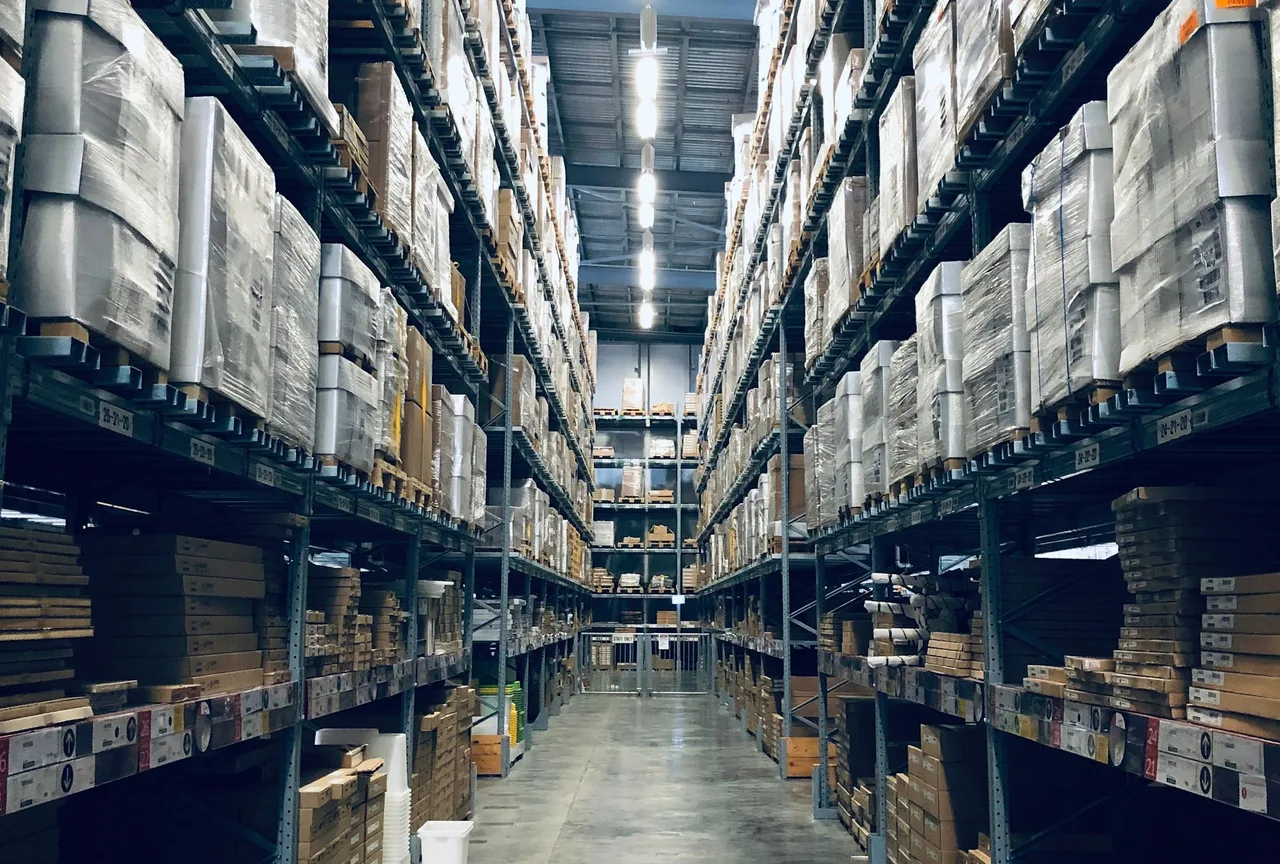 Distribution warehouse aisle stacked with palletized inventory where temporary staffing crews work